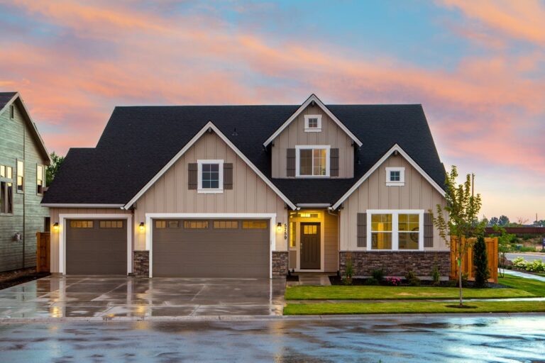 A brown and gray painted house in front of the road with brown garage doors